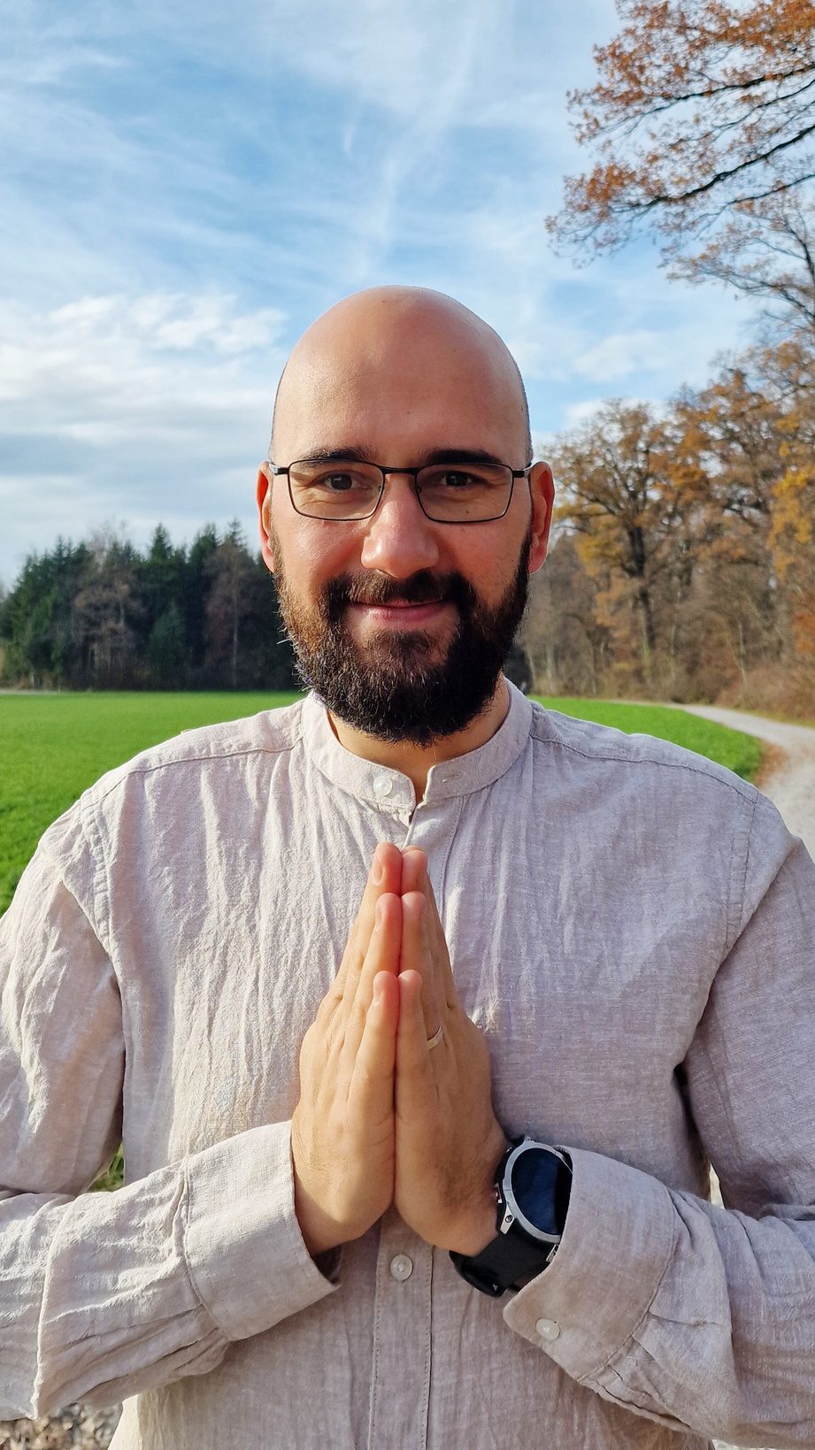 Flavius standing outdoors with hands together in greeting