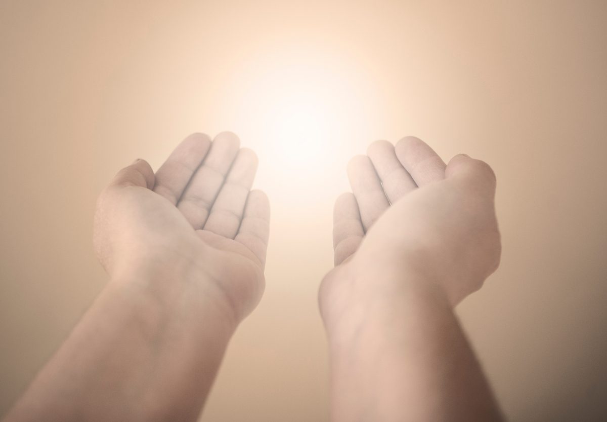 Open hands held toward soft light