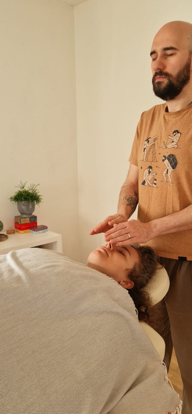 Flavius giving a Reiki session to a person lying down
