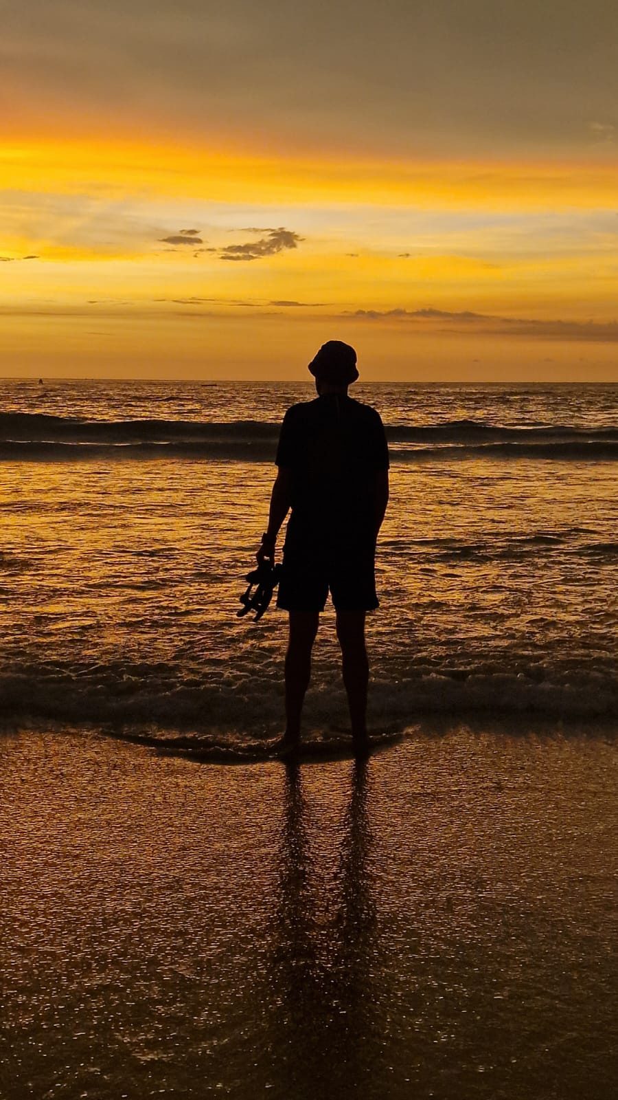 A silhouette standing at the shore at sunset